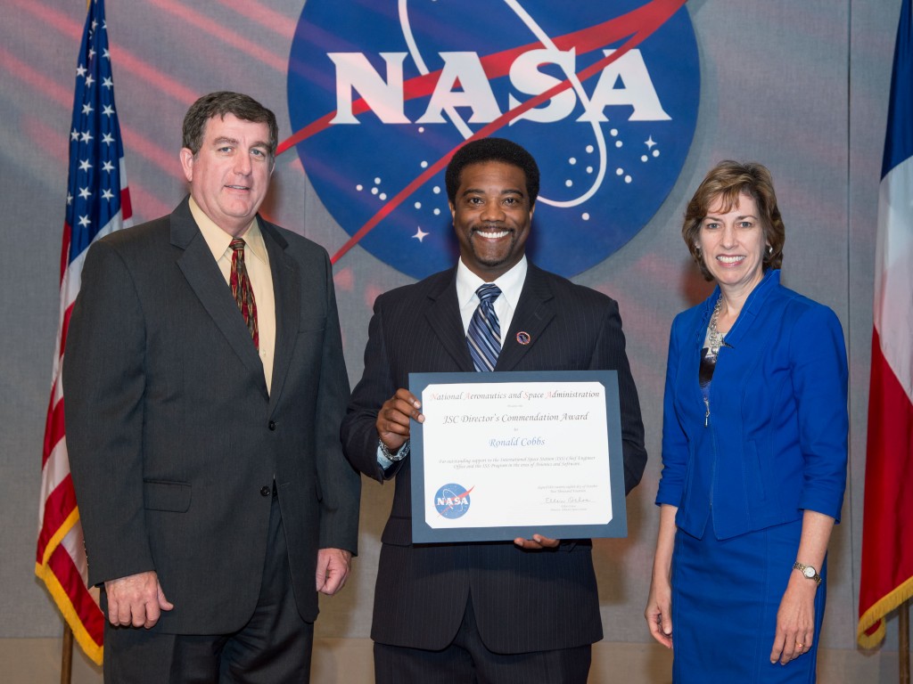 NASA Johnson Space Center Director, Dr. Ellen Ochoa, right; and Deputy Director Kirk Shireman, left, congratulate Ron Cobbs after presenting him with the NASA-JSC Director’s Commendation Award, during a ceremony recently in the Teague Auditorium at the center.